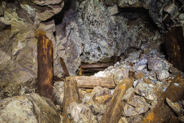 Underground abandoned platinum ore mine tunnel with collapsed wooden timbering