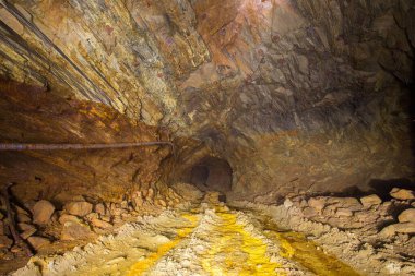 Terk edilmiş bakır madeni, yer altı tüneli ve sarı toprak.
