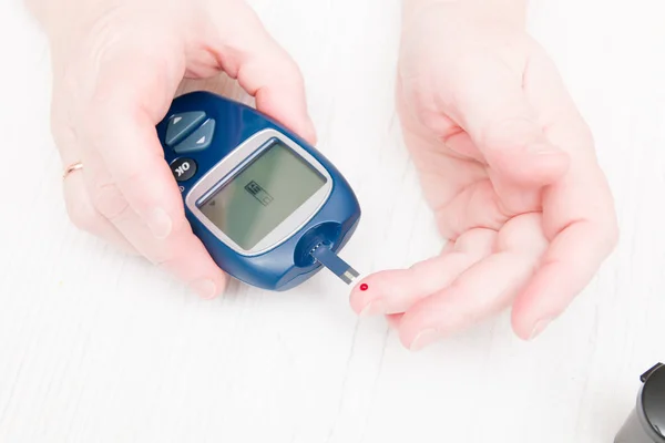 女性的手测量血糖 手指上的一滴血和血糖表 糖尿病做血液检测 糖尿病概念 — 图库照片