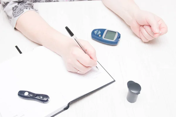 woman holds a pen to record the results of a glucose test, diabetes concept, blood sugar control