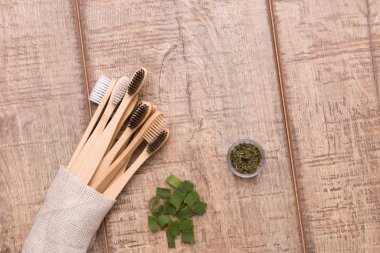 Bambu diş fırçaları ve ahşap bir masada bir avuç aloe dilimleri, bir kavanoz kurutulmuş nane, doğal kozmetik, çevre dostu kavram.