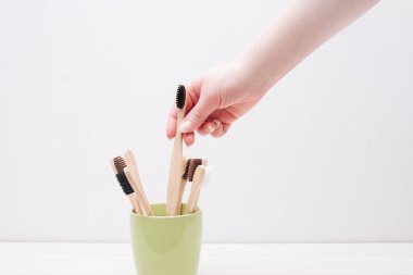 Kadın eli bambu fırçasını birkaç fırçayla birlikte bir bardaktan alır, çevre dostu kavram, sıfır atık