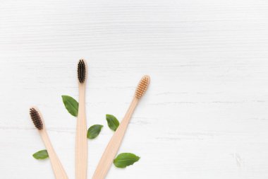 three bamboo toothbrushes fan out lie on a light wooden background association with trees, plastic free clipart