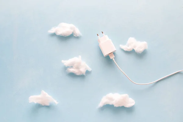 white usb cable with charger like a kite flying into the sky with clouds, cotton and blue background, copy space, saving energy and saving natural resources concept