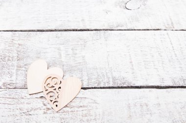 two wooden hearts on white wooden boards, aged wooden table, light background, copy space, heart with carved patterns, decoration for Valentine's day and birthday, mother's day
