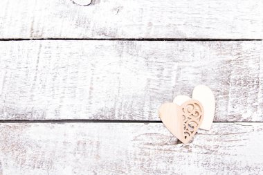 two wooden hearts on white wooden boards, aged wooden table, light background, wood texture, copy space, heart with carved patterns, decoration for Valentine's day and birthday, mother's day