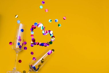 İki cam şampanya kadehi konfeti, parlak daireler, sevgililer günü konsepti, düğün günü, sevgililer günü randevusu, kopyalanacak yer, konfetiden kalp serpiştirilmiş sarı arka plan değil.