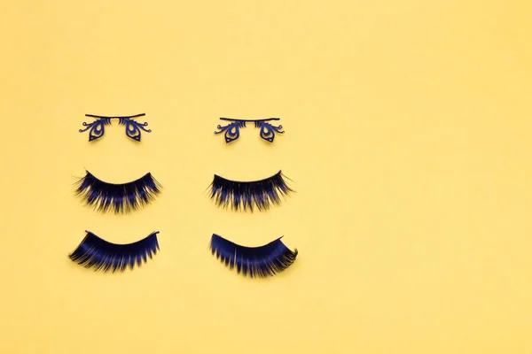 three pairs of different false eyelashes on a yellow background copy space top view, fluffy black eyelashes, butterfly-shaped eyelashes