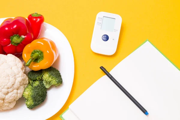모니터를 노란색 배경으로 야채가 흰색의 커다란 장치를 검사한다 섭취와 — 스톡 사진