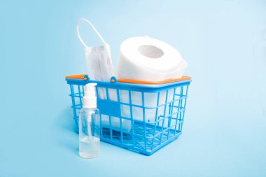 Tıbbi koruyucu maskeli plastik mavi alışveriş sepeti, antiseptik, tuvalet kağıdı, karantina 2020, koronavirüs salgını, mavi arkaplan kopya alanı