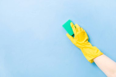 Sarı lastik eldiven içinde bulaşık ve temizlik için yeşil bir sünger, mavi arka plan fotokopi alanı, temizlik konsepti, ev işleri, bahar temizliği