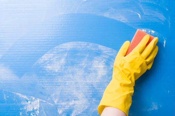 stock image a female hand in a yellow rubber glove washes a blue surface of dirt with a paralon sponge, scattered white powder for cleaning, a wet sponge left a clean mark, cleaning before and after the concept, copy space, top view