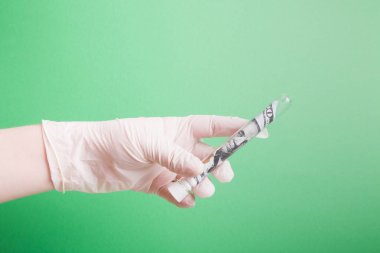 Cam test tüpünde yüz dolarlık banknot, tek kullanımlık beyaz plastik eldivenli bir el yeşil arka planda test tüpü tutuyor, kopyalama alanı, 2020 krizi, ABD 'de koronavirüs salgını.