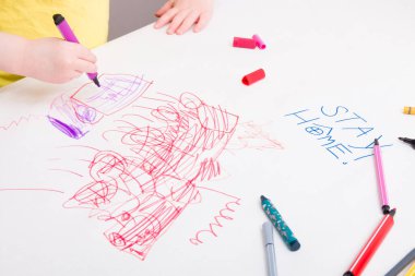 Sarı tişörtlü küçük bir çocuk, karantina süresince çocuğa ne yapacağına dair büyük bir sayfa kağıt çizer. Anaokulu çocuklarının gelişimi, yazıtlar bir sayfa kağıda yazılır, çoğaltılır.