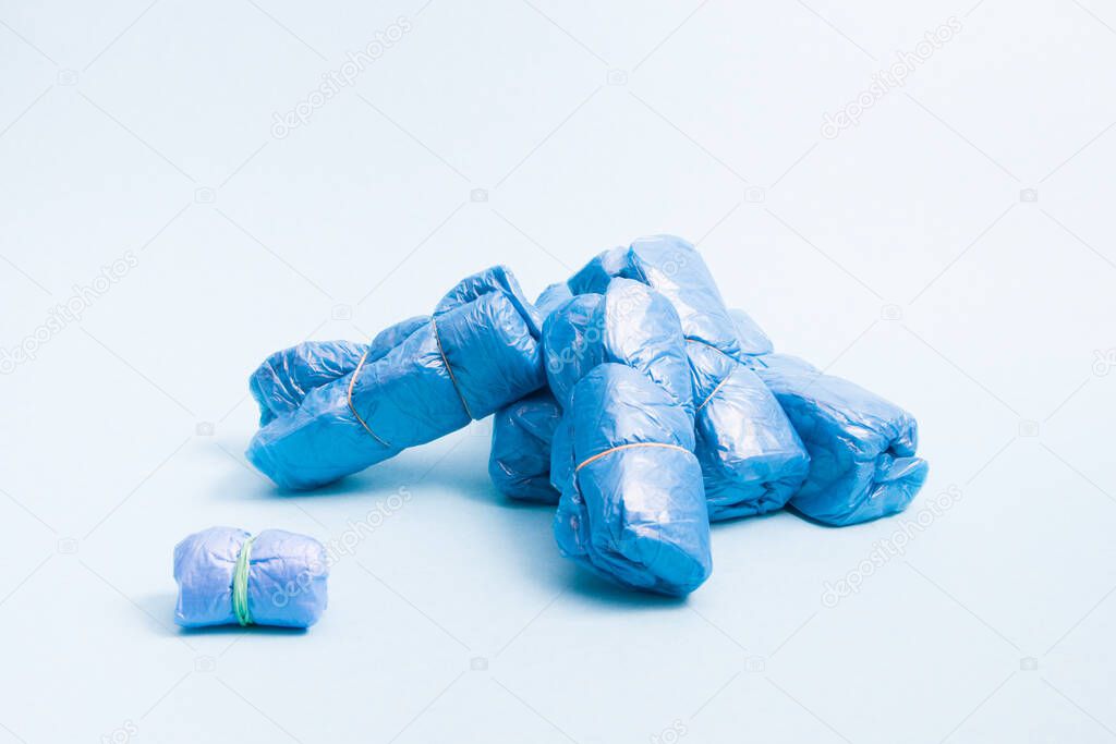 many bundles of blue shoe covers on a blue background, copy space, a small bundle of shoe covers tied with an elastic band