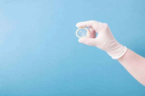 Ruka Bílé Gumové Rukavice Drží Kondom Bez Obalu Modrém Pozadí — Stock fotografie