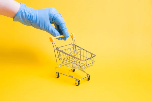 Hand Blue Disposable Rubber Glove Holds Miniature Shopping Trolley Handle — Stock Photo, Image