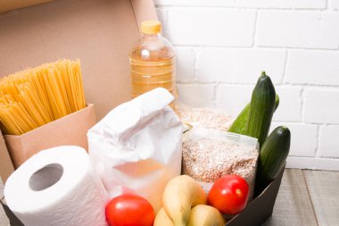 Bir kutuda bağış için yiyecek, sarı arka plan, kopya yeri, bağış kutusu, tuvalet kağıdı ve gıda ürünleri, gönüllü ve kendi kendini izole etme yardımı, temassız dağıtım konsepti,