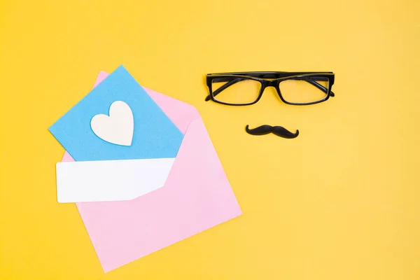 Glasses Mustache Pink Envelope Wooden Heart Card Yellow Background Top — Stock Photo, Image