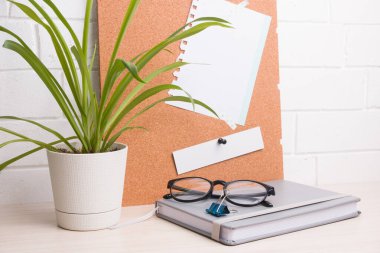 Evde iş yeri, defter, gözlük ve mantar bir kızın arka planında saksı ve beyaz tuğla bir duvar, kopyalama alanı, çalışma ve ev konsepti.