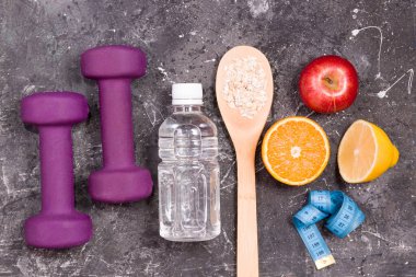 Bir şişe su, dambıl, mezura, siyah arka planda diyet yiyecekler, fotokopi alanı, üst görünüm, meyveler, tahta kaşıkta yulaf ezmesi, kilo kaybı ve sağlıklı yaşam tarzı kavramı.