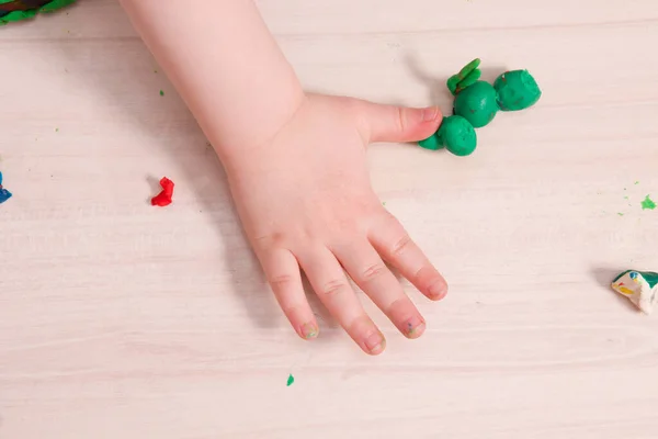 a small child sculpts from plasticine on a wooden table, the development of fine motor skills of hands, than to occupy a child at home, stay at home