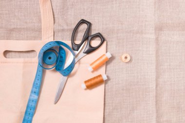 Eko torba, makas, mezura ve keten kumaş, üst görünüm, kopyalama yeri üzerinde birkaç makara iplik. Çevresel materyaller, keten dokusu