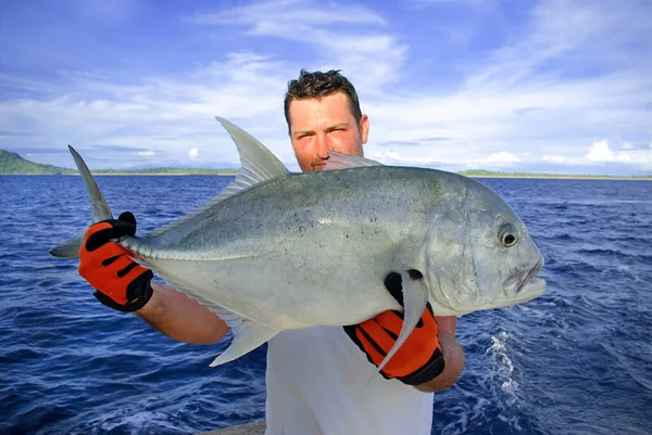 深海釣り 魚を捕まえろ トレバリージャックの魚を持っている男 ロイヤリティフリーのストック画像