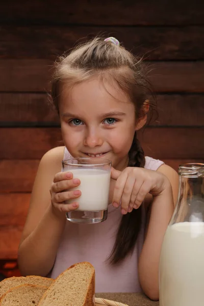 Niedliches kleines lächelndes Mädchen hält ein Glas Milch in der Hand — Stockfoto