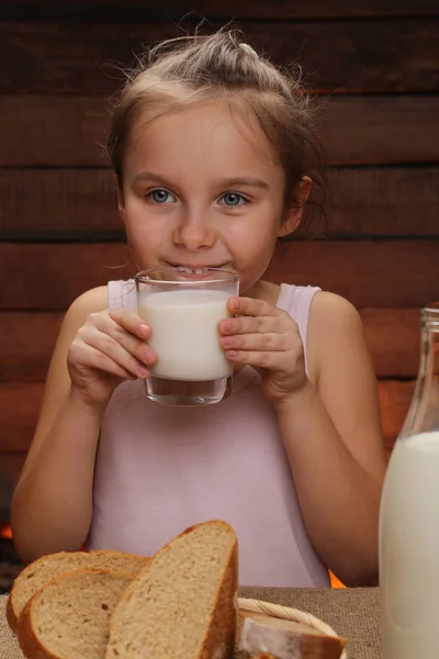 Ładna dziewczynka uśmiechający się trzyma szklankę mleka — Zdjęcie stockowe