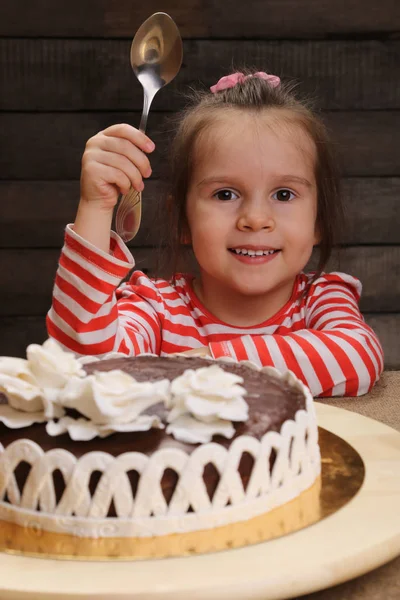 Dziewczynka z miarką w ręku zamiar zjeść ciasto czekoladowe — Zdjęcie stockowe