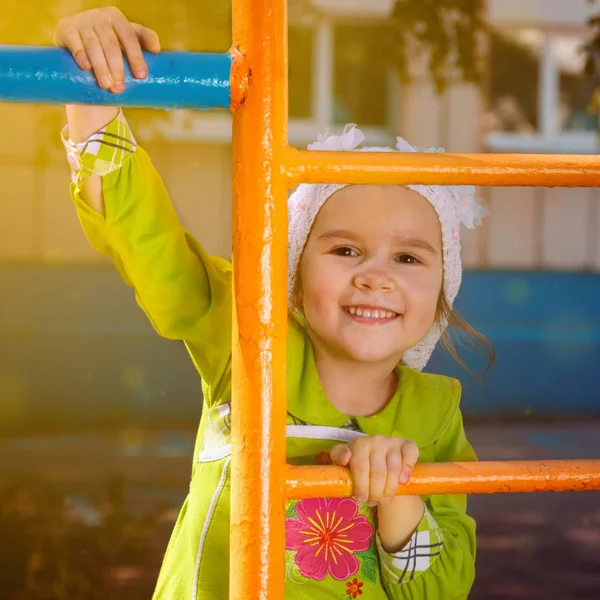 Счастливая маленькая девочка играет на детской площадке — стоковое фото