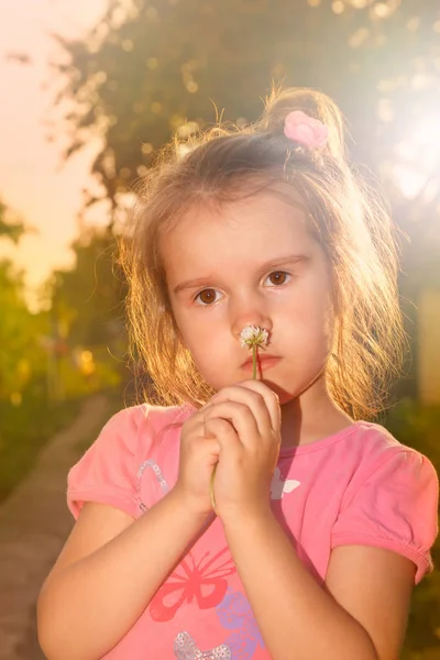 Dziewczynka z kwiatami na zachód słońca promienie słońca — Zdjęcie stockowe
