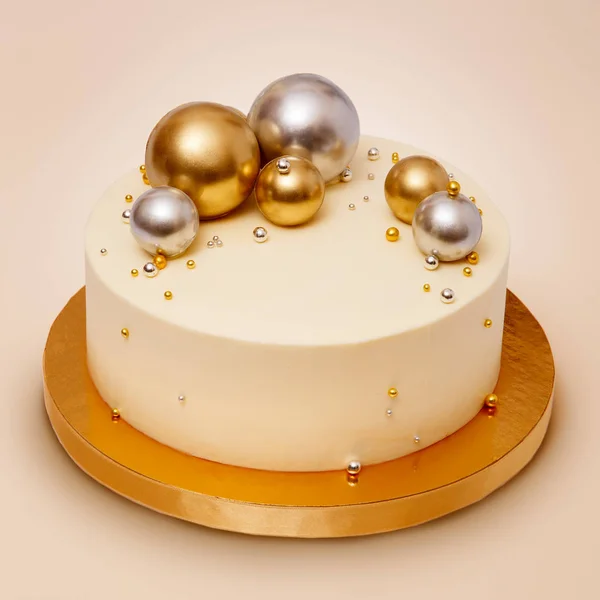 A classic cake with white frosting decorated on the top chocolate balls