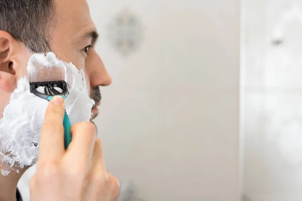 Golenie człowieka na piance z brzytwa mirron w łazience — Zdjęcie stockowe