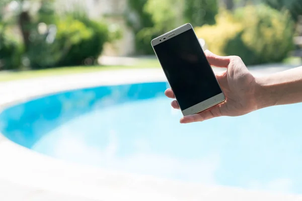 Weibchen Steht Sommer Der Nähe Des Pools Und Zeigt Smartphone lizenzfreie Stockbilder