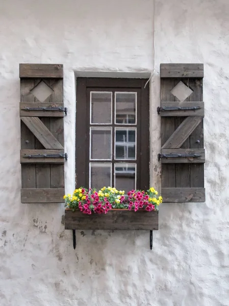 Holzfenster Alte Steinmauer Auf Der Straße Mit Bunten Blumen Riga lizenzfreie Stockbilder