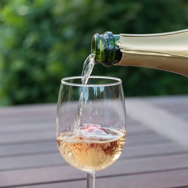 Despejando champanhe em um copo em um jardim — Fotografia de Stock