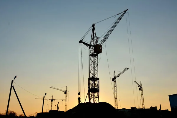 Silhuetas de guindastes de torre no fundo do pôr do sol — Fotografia de Stock