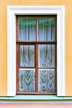 Evin sarı duvarına karşı kahverengi ahşap çerçeveli dikdörtgen pencere. Saint Petersburg Windows dizisinden..