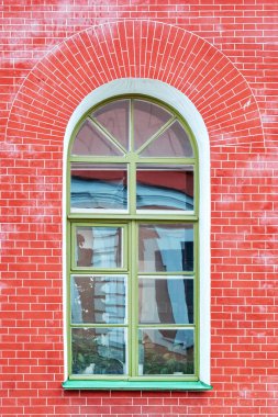 Kırmızı tuğlalı duvarın arka planında yeşil pencere pervazı olan bir pencere. St. Petersburg 'un bir dizi penceresinden.