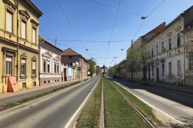 Szeged, Macaristan, 11 Nisan 2020 'de güneşli bir bahar gününde Szeged şehrinde bir koronavirüs karantinası sırasında terk edilmiş bir caddenin görüntüsü.