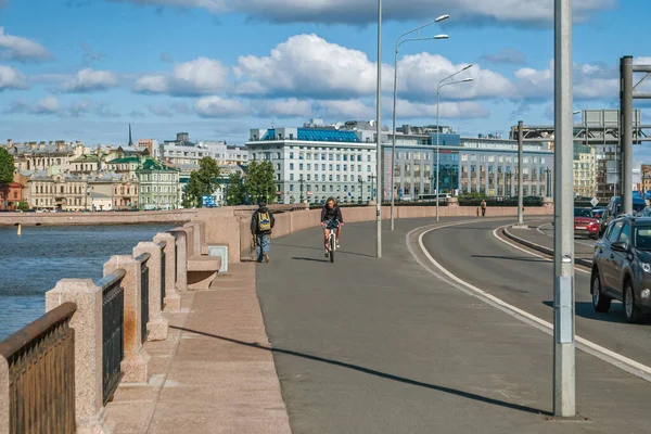 Saint Petersburg, Rusya, 7 Haziran 2016: Güneşli bir yaz gününde Pirogovskaya seti boyunca bisiklet süren bir bisikletçi.