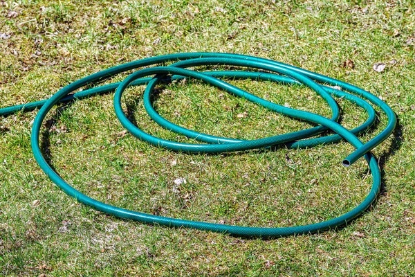 Pokręcony Pierścień Zielonego Wzmocnionego Węża Ogrodowego Leży Zielonej Trawie — Zdjęcie stockowe