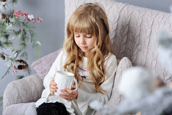 Happy little smiling girl with cosy cup near Christmas tree — Stock Photo, Image