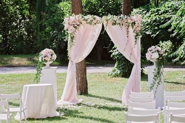 Арка для свадебной церемонии, украшенная тканью и цветами — стоковое фото