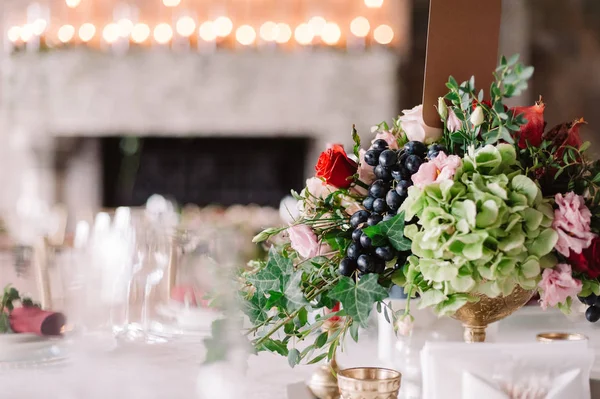 Украшение свадебного стола красными и розовыми цветами, виноградом и зеленью — стоковое фото