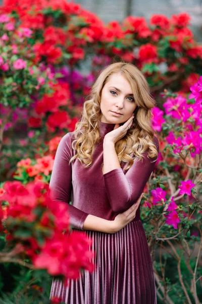 Junge hübsche Frau zwischen roten Blumen — Stockfoto