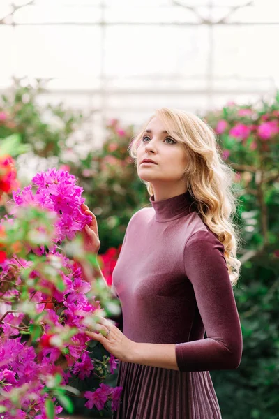 Unga vackra wooman mellan röda blommor — Stockfoto