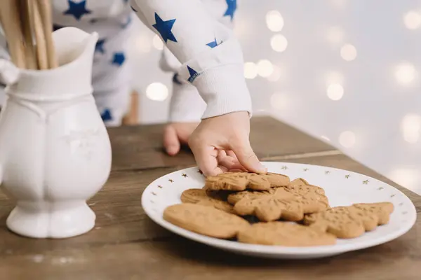 Child hand holding a gingerbread new year tree with Christmas lights on background. Festive bold bokeh — Stock Photo, Image